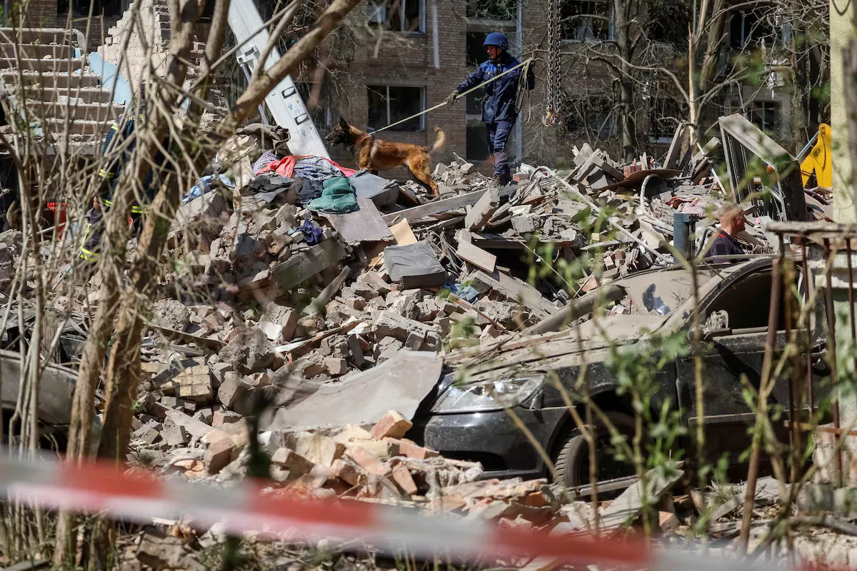 Рятувальник зі службовим собакою шукає мешканців, які все ще можуть бути під гумою зруйнованого житлового будинку, який постраждав під час російського ракетного удару, під час нападу Росії на Україну, у Києві, Україна, 24 квітня 2025 року
